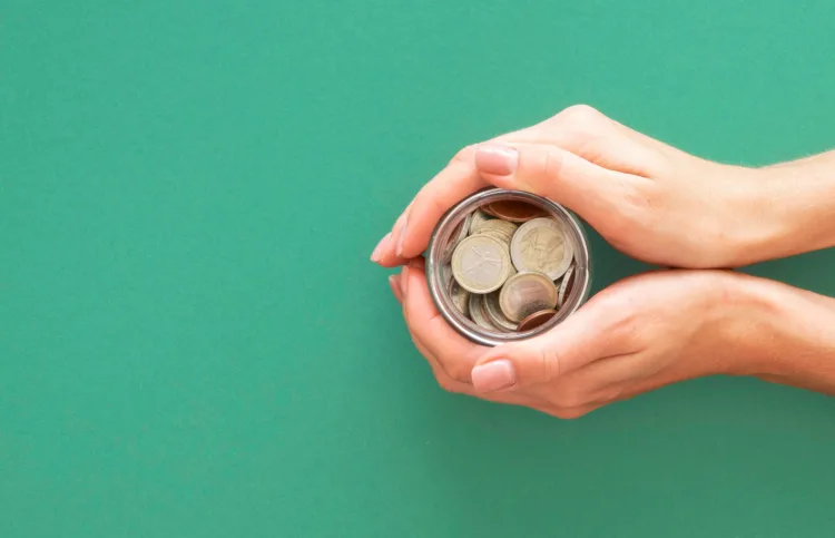 Mãos a segurar frasco de moedas
